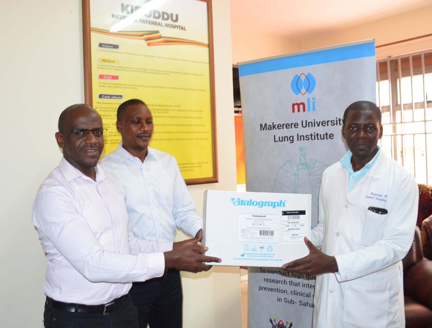 From the right, Simon Mugambe Head of Operations Makerere University Lung Institute, Dr Ivan Kimuli head Clinical Services Makerere University Lung Institute hand over a mouth pieces for the Vitalograph Machine to Robert Buyungo the Spirometry technician at Kiruddu National Referal Hospital on 27th February 2024